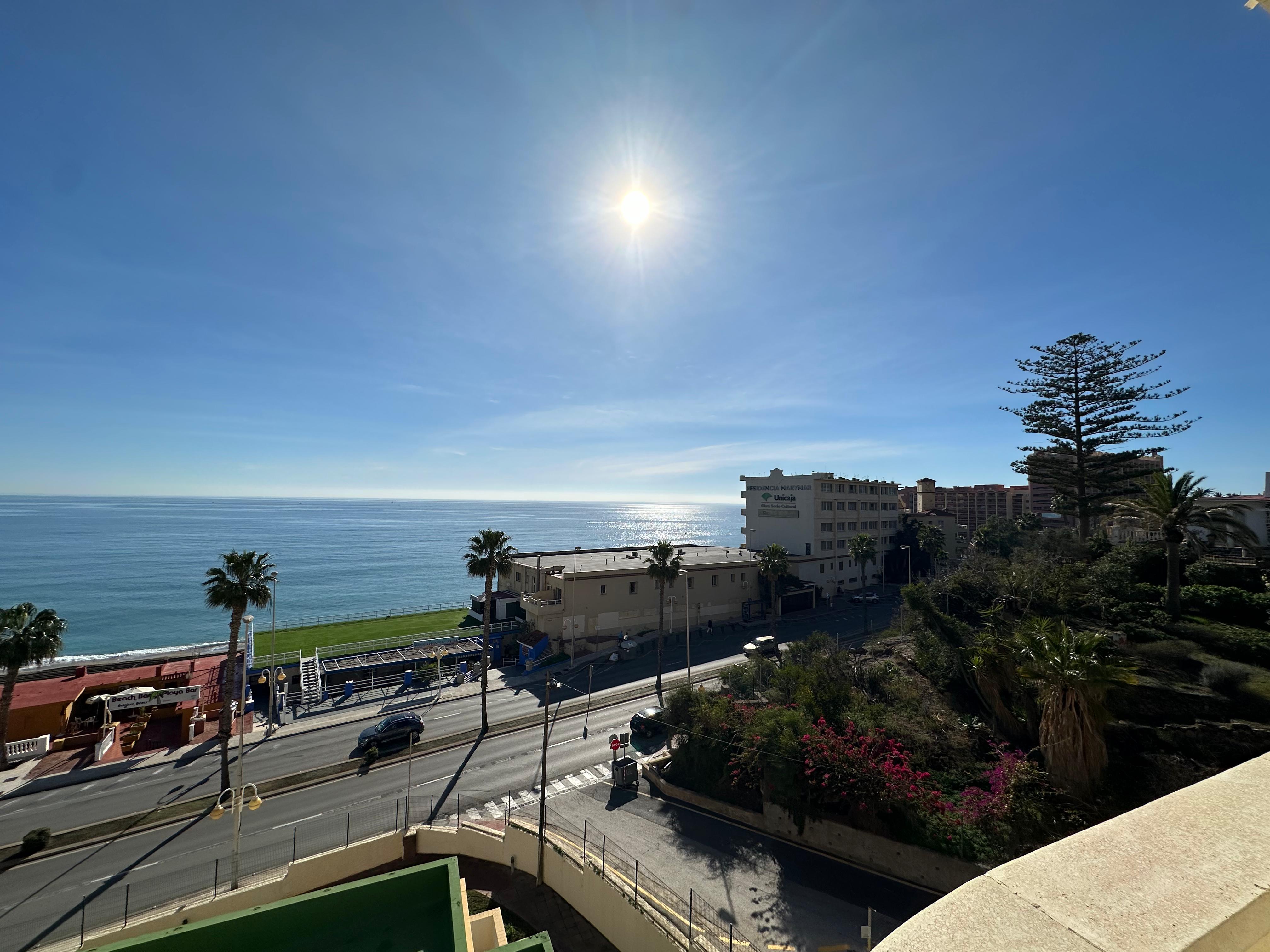 Vistas al mar desde la terraza de un apartamento turístico en Benalmádena, con el paseo marítimo y palmeras